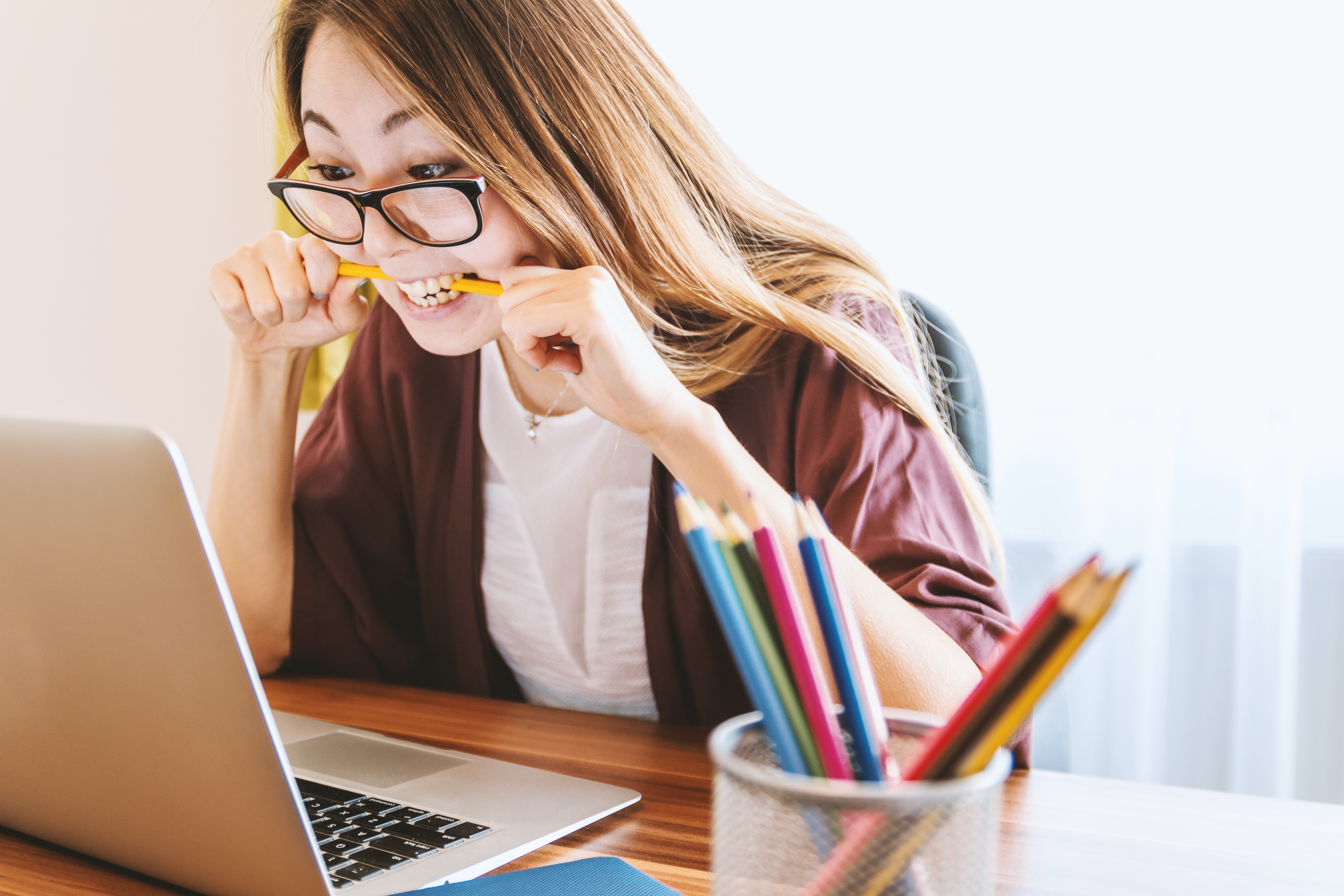Image of a woman at her desk biting on a pencil looking very frustrated