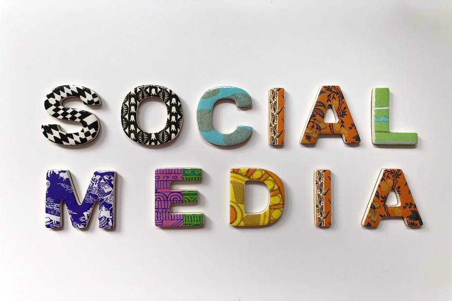 Image of social media written in multi-coloured & patterned cut out letters against a white background