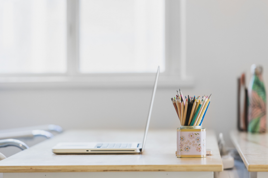 Clean image of a desk, laptop & pencil pot. There is a lot of white space, to give the impression of a productive workspace