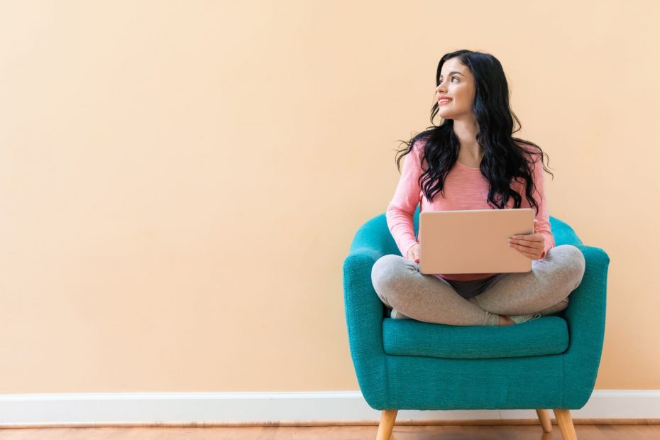 Image of a woman sitting on a chair with a laptop on her lap, looking pleased as she has just signed up to mailerlite for her email marketing !