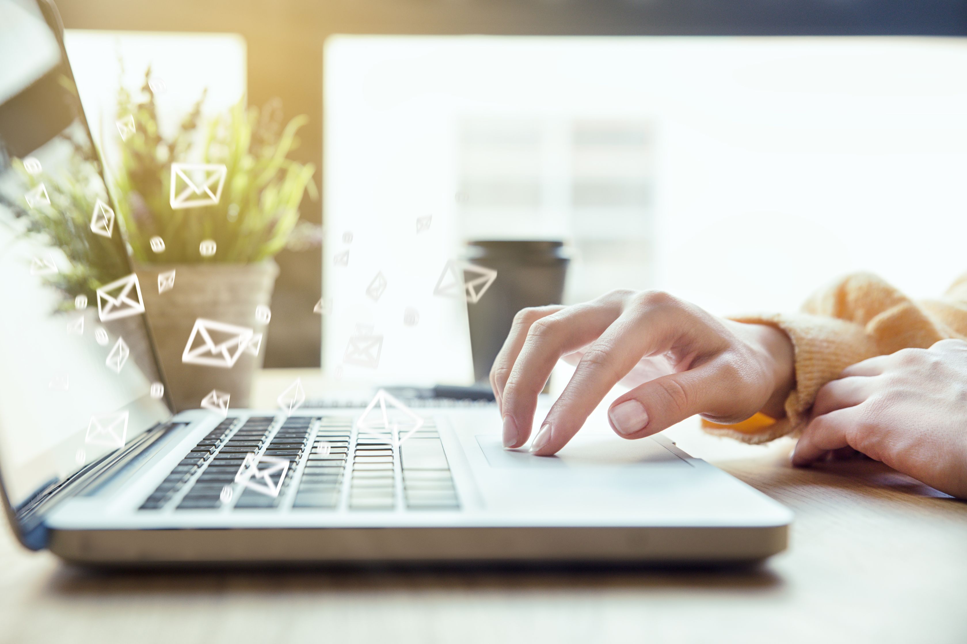 Close up of laptop with woman typing on it. There are illustrated emails coming from the keyboard as if to indicate good email deliverability