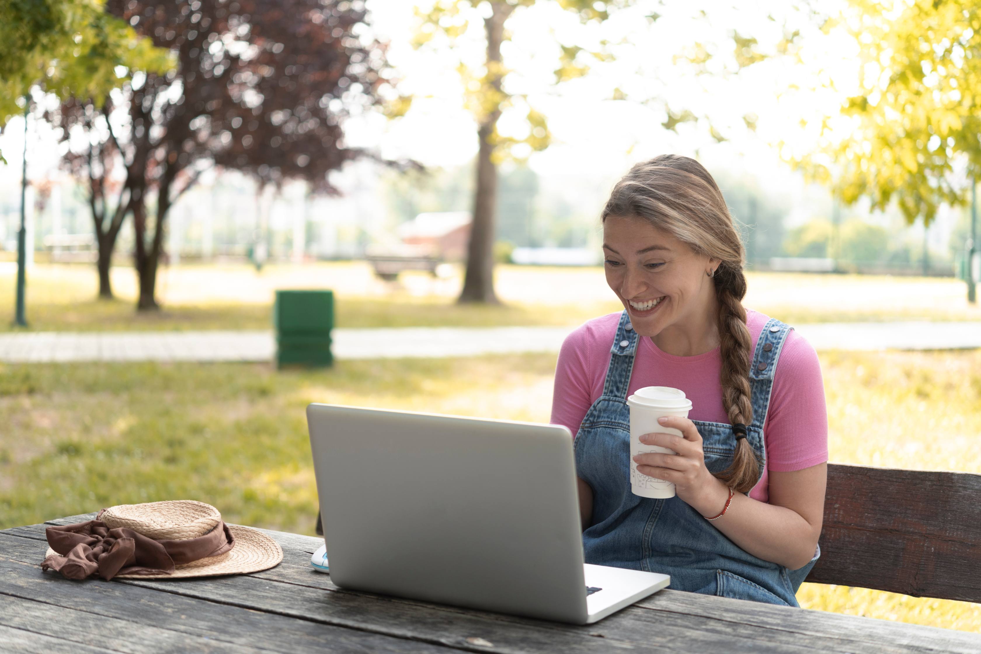 Image of a woman sitting outside in the sunshine working on her laptop