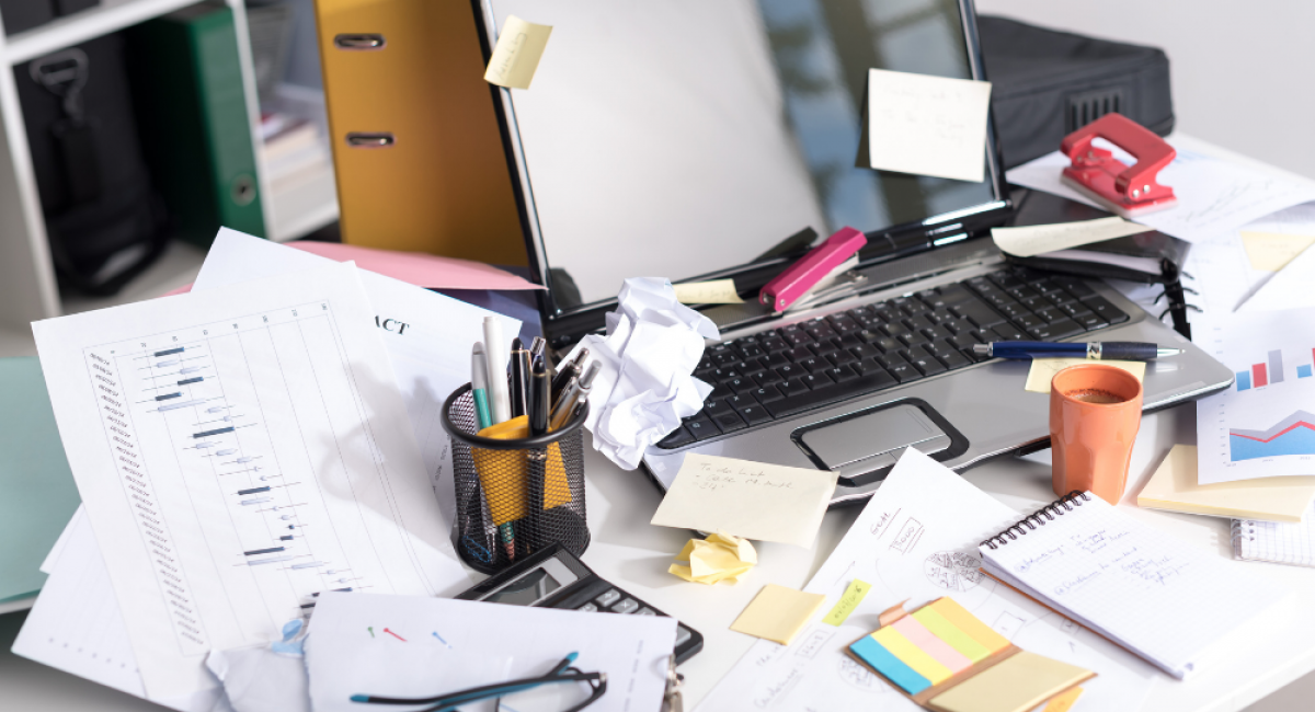 desk covered in paperwork & mess